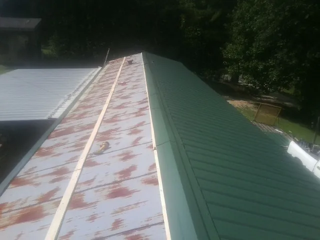 Old rusted panels beside newly installed green metal roofing — Wind Damage Roof Repair by Roofing Brothers in Sandy Lake