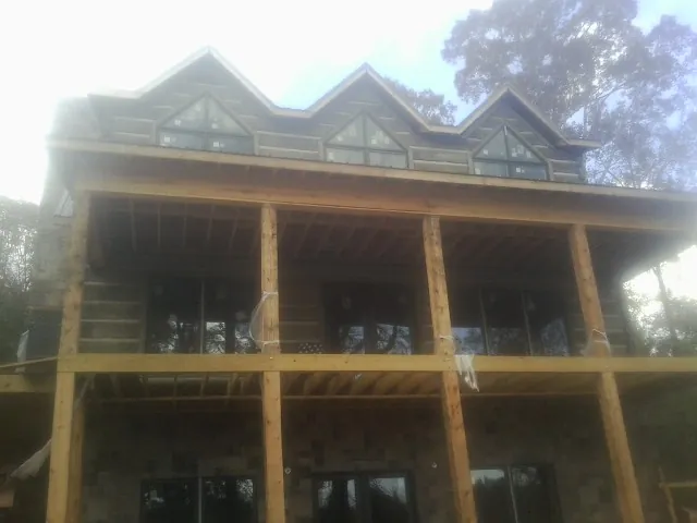 Dormers and porch framing on a large log home under construction — Roof Coating work by our crew in Sandy Lake