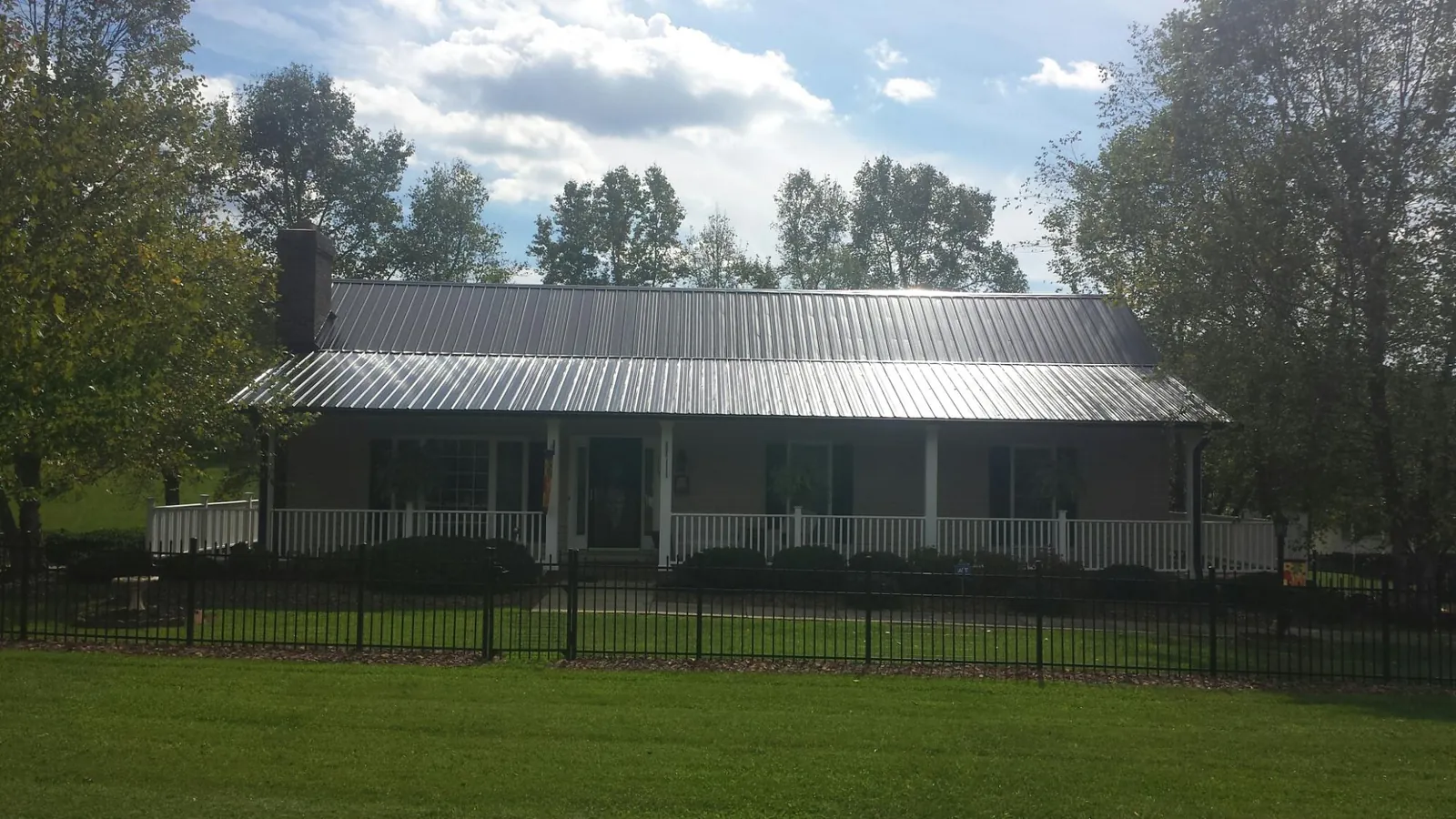 Gray metal roof on a brick ranch with a full width front porch — Gutter Guard Installation work by our crew in Sandy Lake