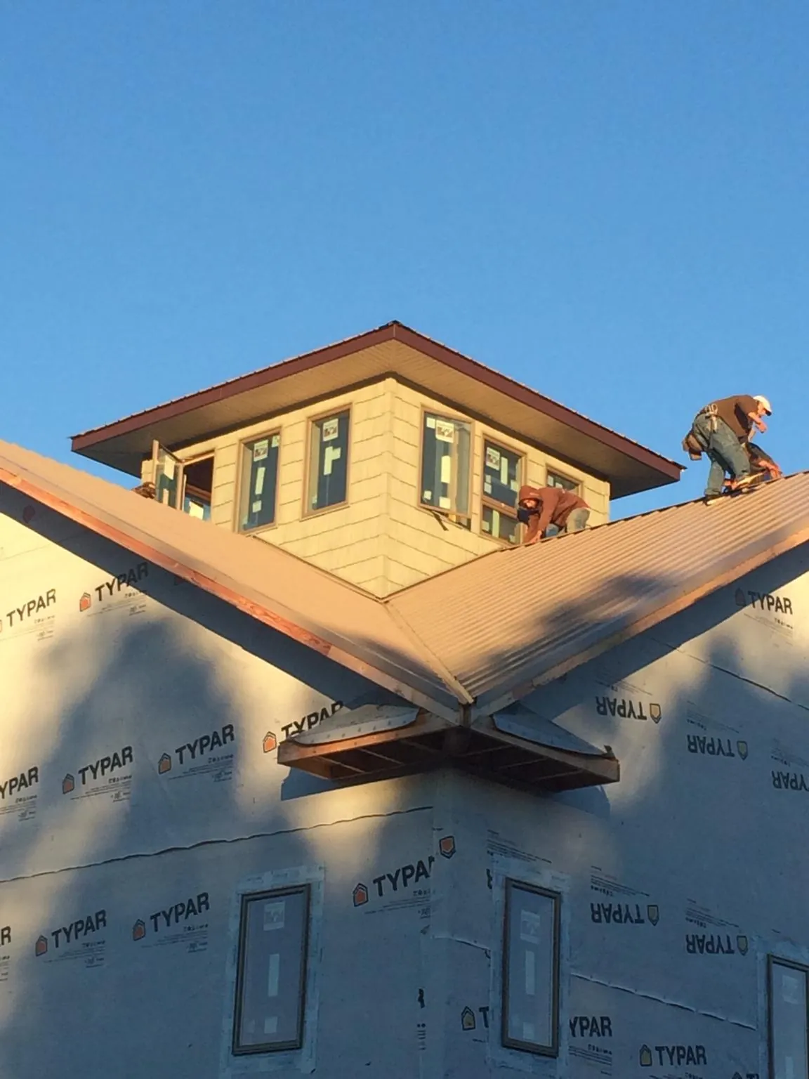 Roofers working around a rooftop cupola on a new metal roof at sunset — Roof Waterproofing in Sandy Lake by Roofing Brothers